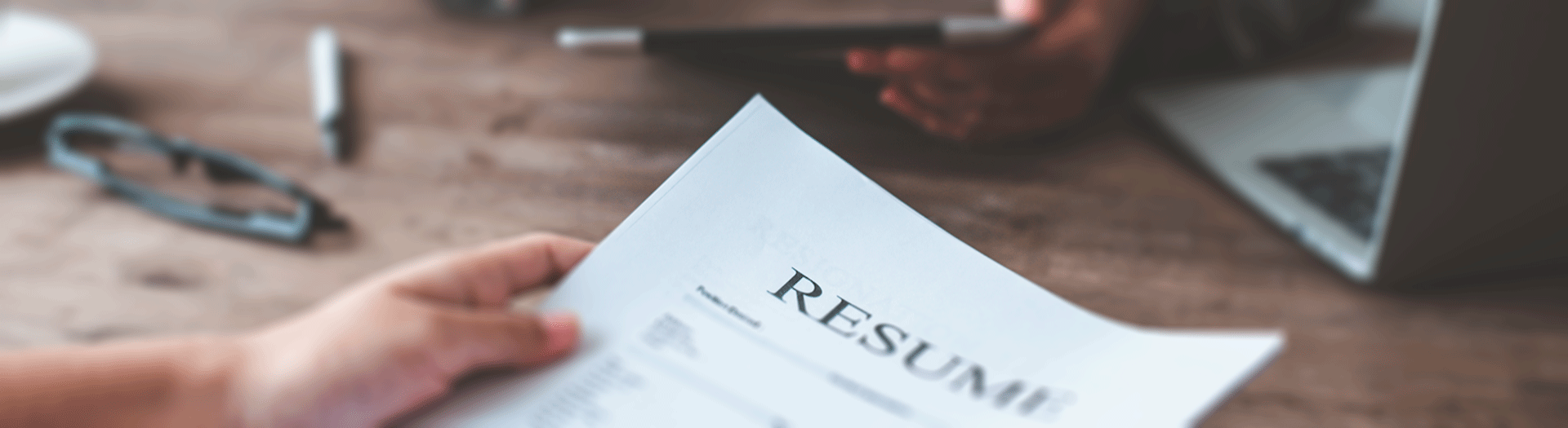Hand with Resume on table with interviewer